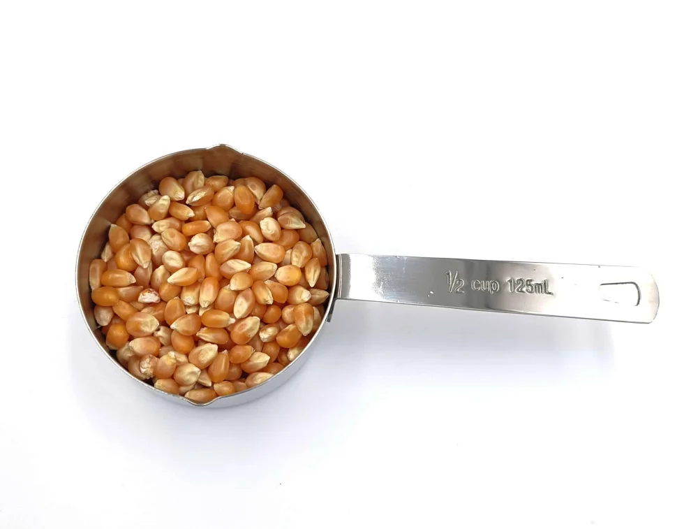 Edelstahl-Messbecher mit 125 ml Volumen, gefüllt mit Popcornmais, ideal für kleinere Portionen.